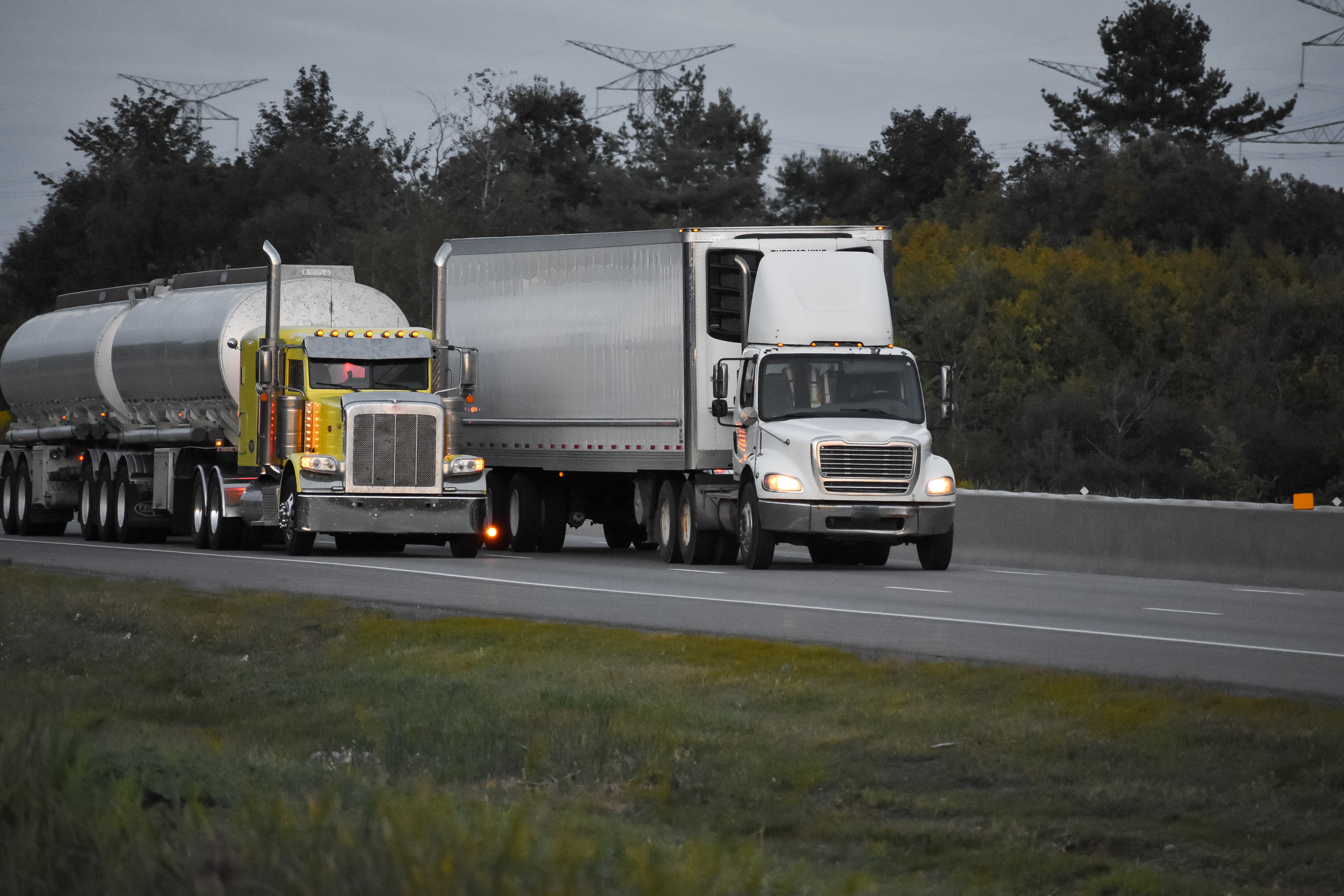 trailer trucks driving road surrounded by beautiful green trees